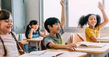 Children in a fun classroom raise their hands