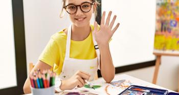 Teenaged student waving hello as they paint