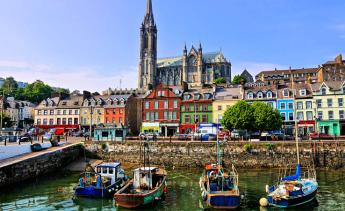 Photo of boats on a river near colorful buildings and a church.