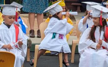 Child looking through diploma at graduation