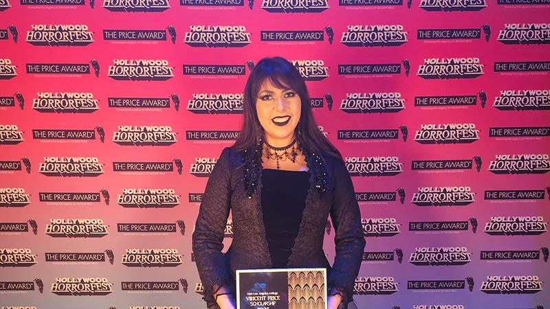Photo of student holding a certificate in front of a step and repeat.