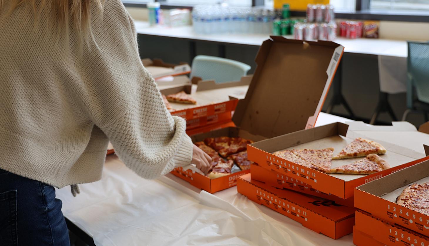 Student grabbing a slice of pizza.